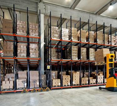 Forklift placing product on a rack in a warehouse