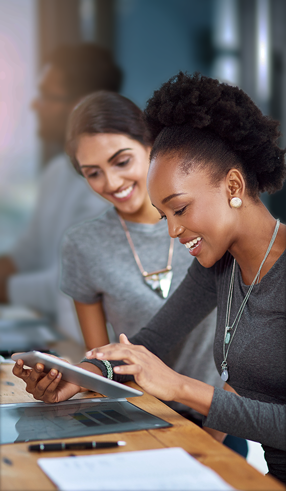 Deux femmes souriantes regardant un iPad Deux femmes souriantes regardant un iPad